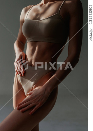 In the sunlight, shadows. Woman with slim body shape is posing against background In the sunlight, shadows. Woman with slim body shape is posing against background 131388903