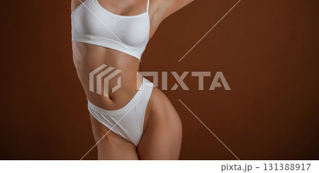 Front view. Woman with slim body shape is posing against background Front view. Woman with slim body shape is posing against background 131388917