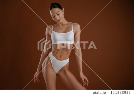 Fashion model. Woman with slim body shape is posing against background 131388932