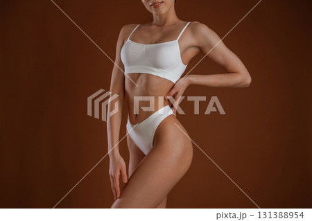 Professional photoshoot. Woman with slim body shape is posing against background 131388954