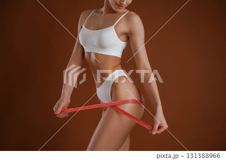 Measuring the leg, conception of weight loss. Woman with slim body shape is posing against background 131388966