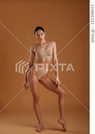 Skinny girl. Woman with slim body shape is posing against background 131389013