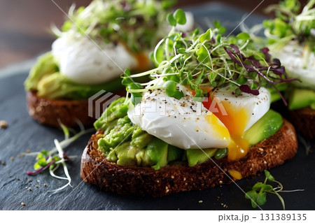 Avocado toast with poached eggs and sprouts is a delightful breakfast. Avocado toast with poached eggs and sprouts is a delightful breakfast. 131389135
