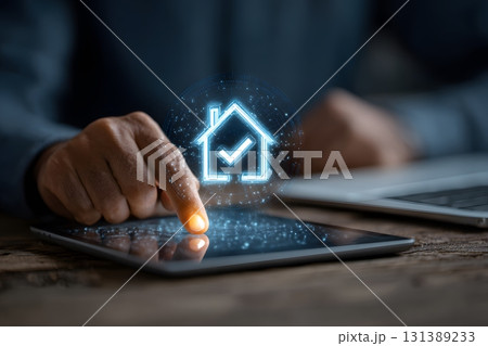 A finger touches a tablet displaying a digital house with a checkmark, representing business. 131389233