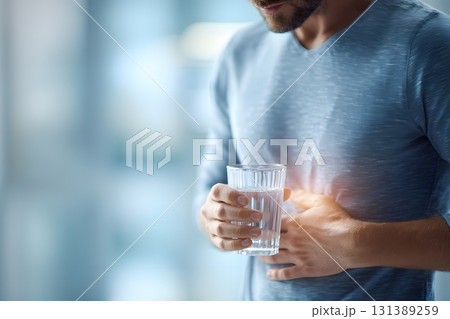 A person drinks clean water to help ease stomach pain. A person drinks clean water to help ease stomach pain. 131389259