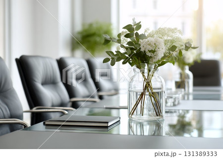 Elegant desk plant decor with fresh flowers in a glass vase on a modern conference table 131389333