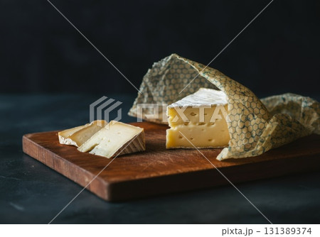 Reusable beeswax wraps showcasing cheese on wooden board with dark background for sustainable living 131389374