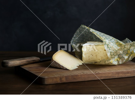 Reusable beeswax wraps with cheese on wooden cutting board showcasing sustainable food storage concept Reusable beeswax wraps with cheese on wooden cutting board showcasing sustainable food storage concept 131389376