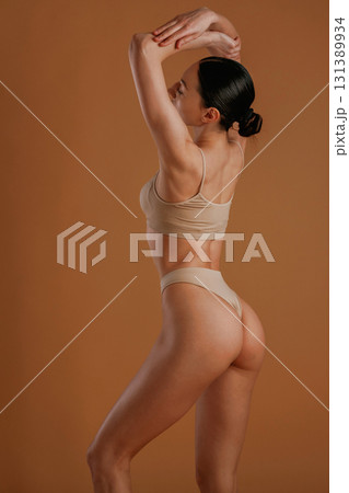 Back and side view. Woman with slim body shape is posing against background 131389934