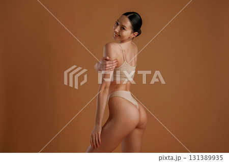 Back and side view. Woman with slim body shape is posing against background 131389935
