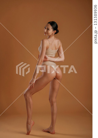 Back and side view. Woman with slim body shape is posing against background 131389936