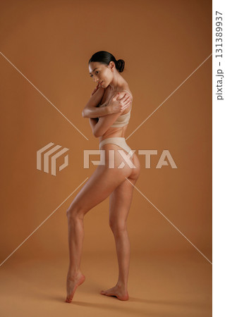 Back and side view. Woman with slim body shape is posing against background Back and side view. Woman with slim body shape is posing against background 131389937