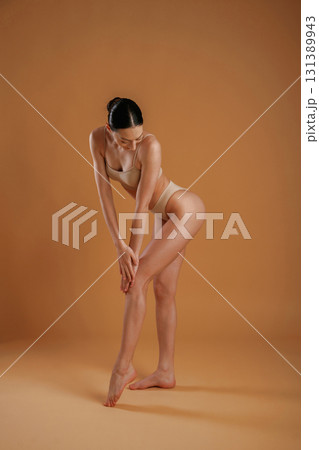 Professional photoshoot. Woman with slim body shape is posing against background 131389943