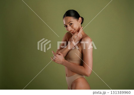 Green background. Woman with slim body shape is posing indoors Green background. Woman with slim body shape is posing indoors 131389960