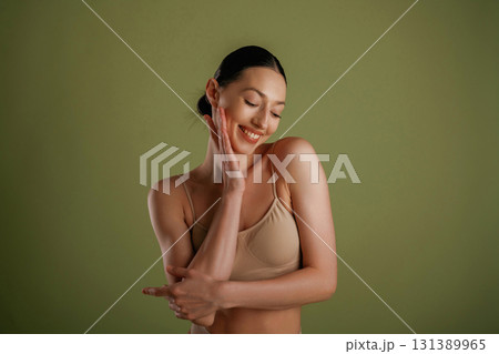 Smiling, cheerful facial expression. Woman with slim body shape is posing against background 131389965