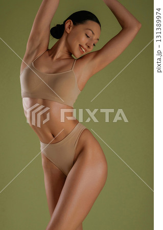 Smiling, cheerful facial expression. Woman with slim body shape is posing against background 131389974