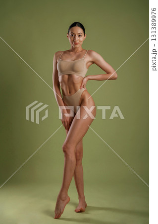 Professional photoshoot. Woman with slim body shape is posing against background Professional photoshoot. Woman with slim body shape is posing against background 131389976