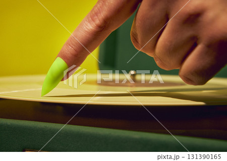Close up of neon green nail finger on vinyl record with surreal creative emotion 131390165