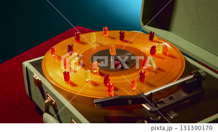 Multicolored gummy bears dancing on vinyl record with joyful surreal emotion 131390170