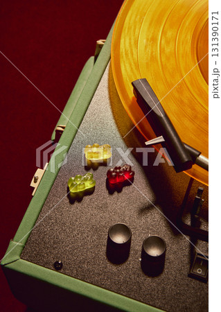 Colorful gummy bears arranged beside golden vinyl record player in creative surreal design Colorful gummy bears arranged beside golden vinyl record player in creative surreal design 131390171