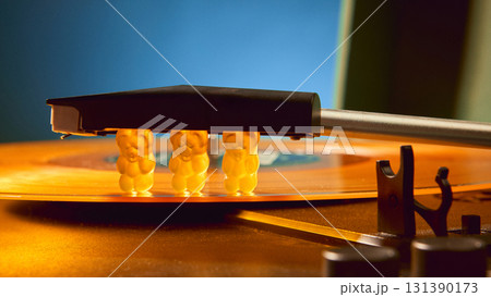 Gummy bears pressed under needle of retro vinyl record player with surreal emotion 131390173