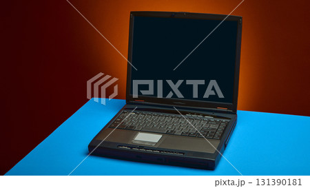 Black retro laptop glowing with mysterious cultural aura on bright blue surface 131390181
