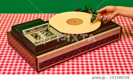Retro vinyl turntable with yellow record and hand adjusting tonearm Retro vinyl turntable with yellow record and hand adjusting tonearm 131390195