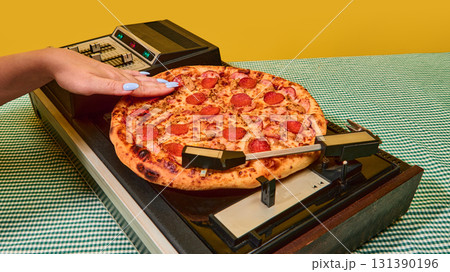 Closeup of hand pressing pizza onto spinning vinyl turntable in retro concept 131390196