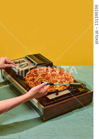 Hands adjusting pizza on old vinyl player with bright yellow backdrop Hands adjusting pizza on old vinyl player with bright yellow backdrop 131390198
