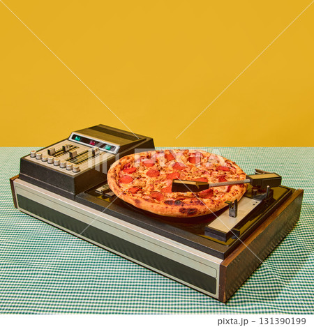 Pepperoni pizza placed on vintage vinyl record player against yellow background 131390199