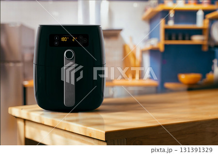 Modern black air fryer on wooden kitchen counter Modern black air fryer on wooden kitchen counter 131391329