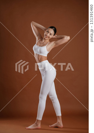 In white clothes. Beautiful fitness woman is in the studio 131391460