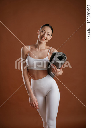 Yoga mat in hand. Beautiful fitness woman is in the studio Yoga mat in hand. Beautiful fitness woman is in the studio 131391461