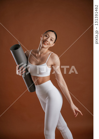 Yoga mat in hand. Beautiful fitness woman is in the studio Yoga mat in hand. Beautiful fitness woman is in the studio 131391462