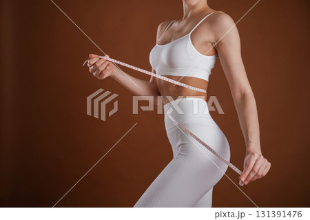 Weight loss and diet conception. With measuring tape. Beautiful fitness woman is in the studio Weight loss and diet conception. With measuring tape. Beautiful fitness woman is in the studio 131391476