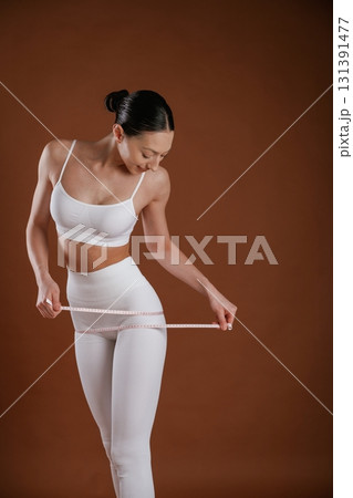 Weight loss and diet conception. With measuring tape. Beautiful fitness woman is in the studio Weight loss and diet conception. With measuring tape. Beautiful fitness woman is in the studio 131391477