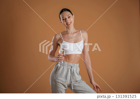 Break, standing and holding bottle of water. Beautiful fitness woman is in the studio Break, standing and holding bottle of water. Beautiful fitness woman is in the studio 131391525