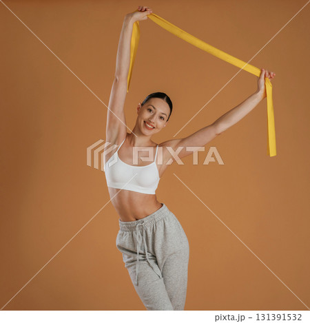 Cloth for stretching hands. Beautiful fitness woman is in the studio 131391532