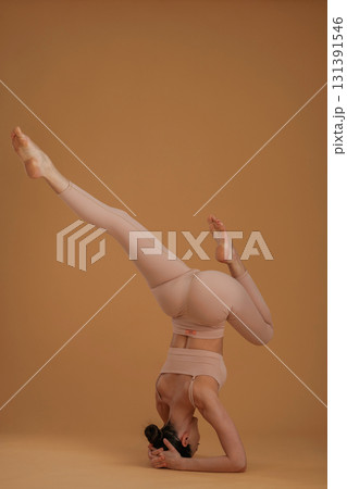 Doing headstand. Beautiful fitness woman is in the studio 131391546
