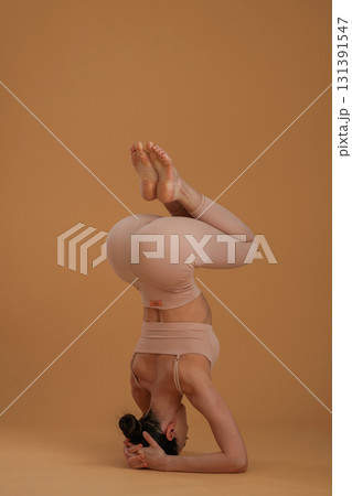 Doing headstand. Beautiful fitness woman is in the studio 131391547