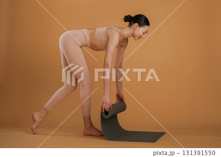 Rolling off the yoga mat. Beautiful fitness woman is in the studio Rolling off the yoga mat. Beautiful fitness woman is in the studio 131391550