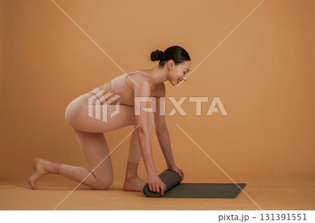 Rolling off the yoga mat. Beautiful fitness woman is in the studio 131391551