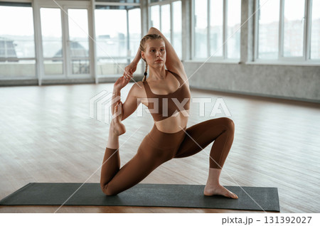 Front view. Warm up exercises. Fitness woman in sportswear is indoors 131392027