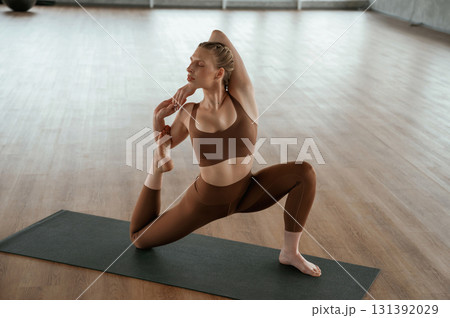 Front view. Warm up exercises. Fitness woman in sportswear is indoors 131392029