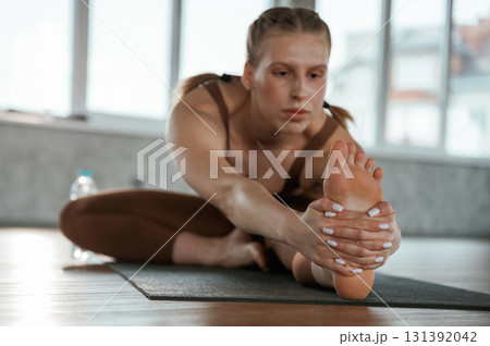 Stretches to the leg. Fitness woman in sportswear is indoors Stretches to the leg. Fitness woman in sportswear is indoors 131392042