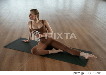 Taking a break, with bottle of water. Fitness woman in sportswear is indoors 131392059