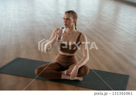 Taking a break, with bottle of water. Fitness woman in sportswear is indoors 131392061