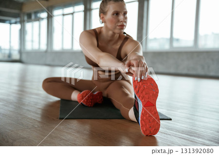Stretching the legs. Fitness woman in sportswear is indoors 131392080