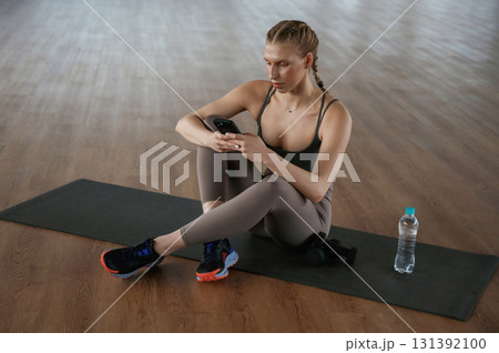 Using smartphone, break. Fitness woman in sportswear is indoors Using smartphone, break. Fitness woman in sportswear is indoors 131392100