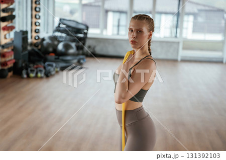 Yellow strap for stretching. Fitness woman in sportswear is indoors Yellow strap for stretching. Fitness woman in sportswear is indoors 131392103